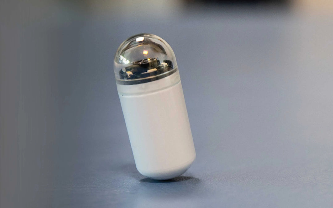 A small, white, capsule-shaped blood glucose monitor with a transparent dome top, branded Sibionics.